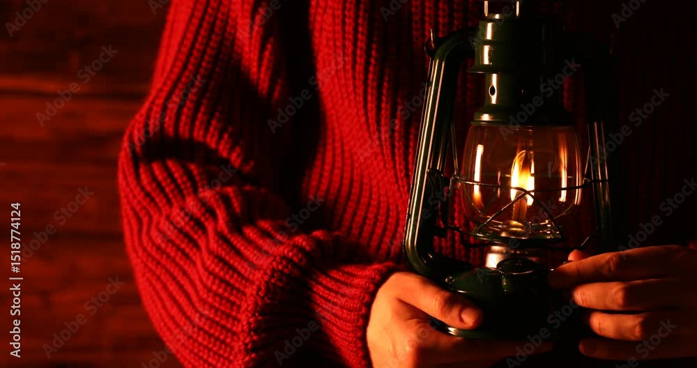 Man turning kerosene lamp on against wooden background, closeup