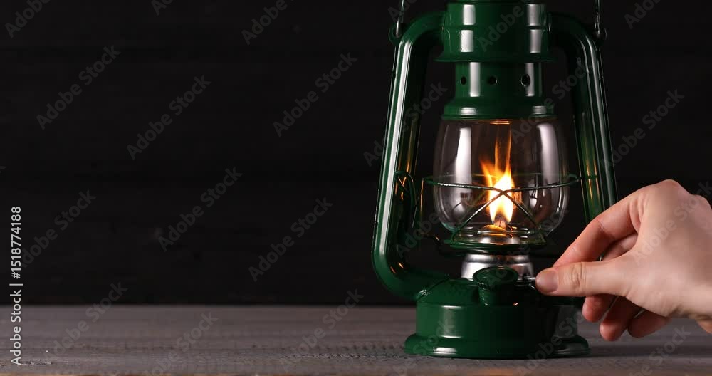 Man turning kerosene lamp on at wooden table, closeup
