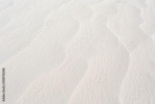 Close-up view of white sand with delicate wind-formed ripples and soft shadows creating a peaceful natural pattern