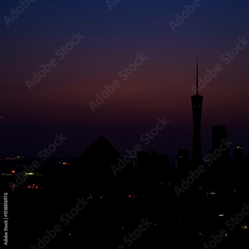 City skyline at night with skyscrapers and a tower under a dark purple and blue sky landscape scene view