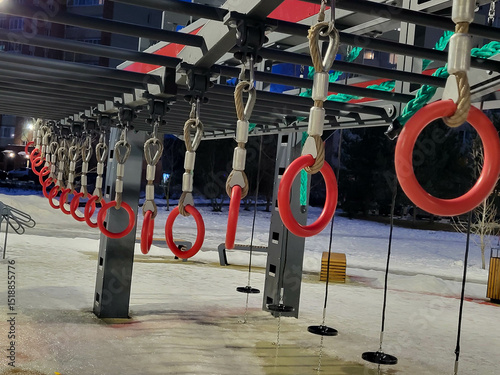 A sports complex with gymnastic rings on the playground in the evening in winter.