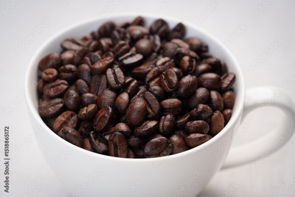 Fototapeta premium Close-up of roasted brown coffee beans piled together, showcasing rich texture, aroma, and freshness on a white studio background.