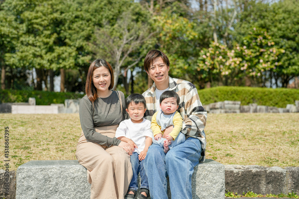 In March, at a sunny park in Fukuoka, a Japanese couple in their thirties sits on a bench with their 3-year-old son and baby girl, 6 months old. This photo captures a peaceful family moment outdoors. In March, at a sunny park in Fukuoka, a Japanese couple in their thirties sits on a bench with their 3-year-old son and baby girl, 6 months old. This photo captures a peaceful family moment outdoors.