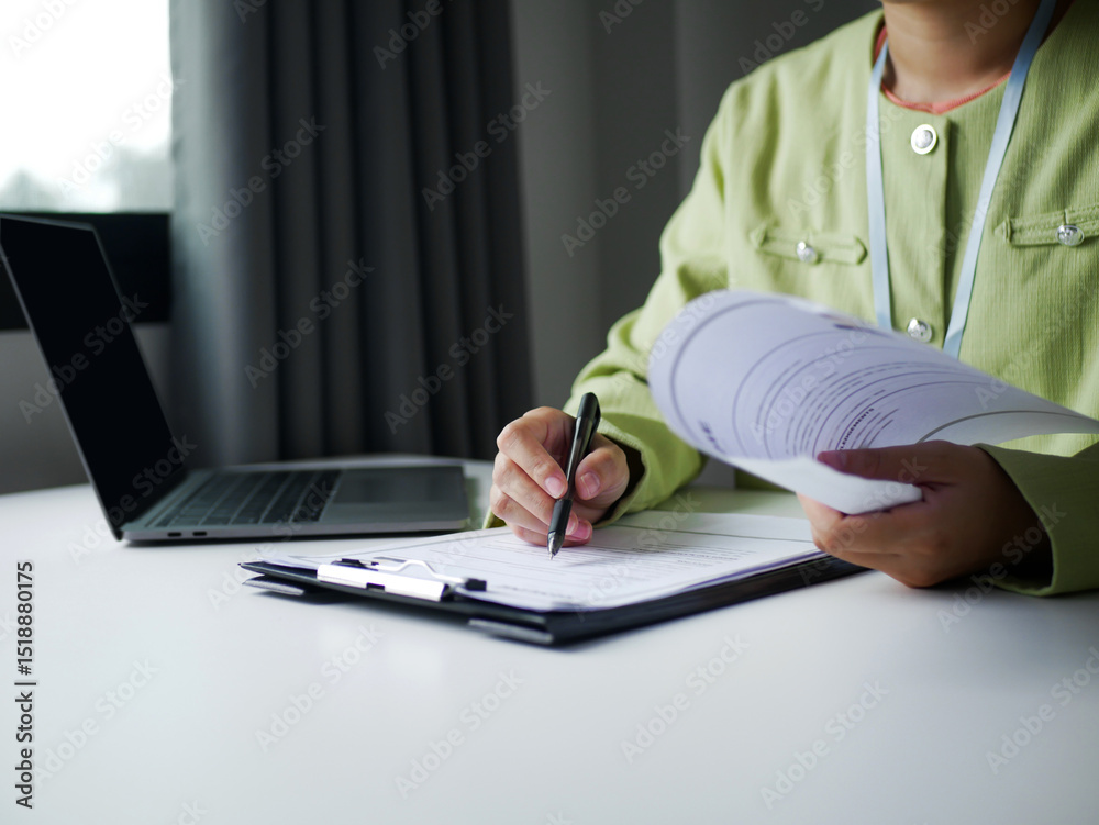 Fototapeta premium Businesswoman is reading a resume to evaluate a job applicant. Sitting reading a resume to hire candidates, analyzing information before an interview. Recruitment concept.