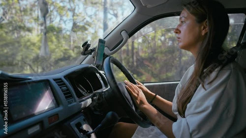 Wallpaper Mural Young woman drives a van through a scenic wooded area during the day. Focused expression shows contemplation and tranquility on this road trip. Torontodigital.ca