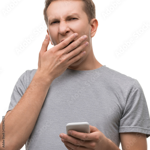 Man yawning while looking at his smartphone in a casual setting