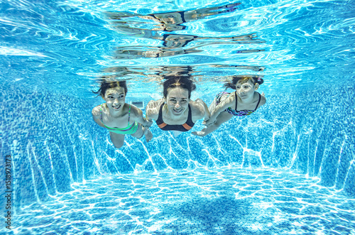 Family swims underwater in swimming pool, happy active mother and children have fun under water, fitness and sport with kids on summer holiday vacation