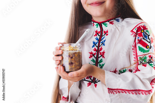Beautiful bulgarian girl wearing traditional folklore costume eating bulgarian sweet meal ashura made from wheat, rose water, nuts and dried fruits