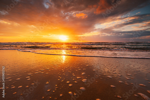 Beautiful cloudscape over the sea beach shore at scenic beauitufl ocean sunrise, splashed waves on the sand