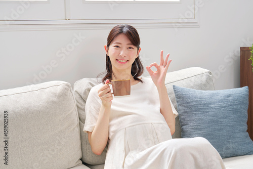 自宅でカフェインレスコーヒーを飲む妊婦　OKサイン