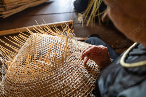 Tableau sur toile Close-up of artisan's hands weaving palm leaves to make traditional conical hats (Non La) in a craft village at ATK Dinh Hoa historical site