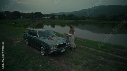 A touching emotional scene unfolds by an old car situated near the waters edge