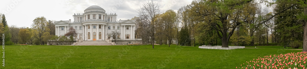 Fototapeta premium Elegant Historic Mansion Surrounded by Vibrant Gardens and Lush Greenery in Early Spring