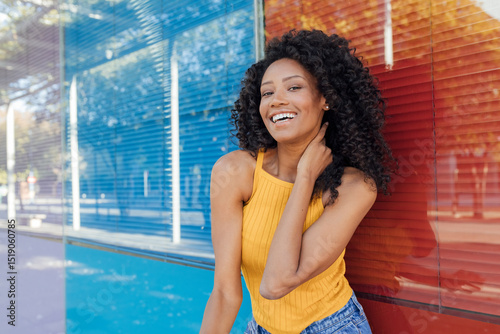 Young woman laughing while standing in front of red and blue glass window