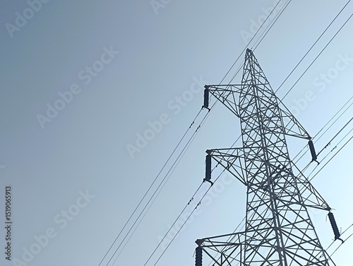 High voltage power lines on towering steel pylons transmit electrical energy across the blue sky