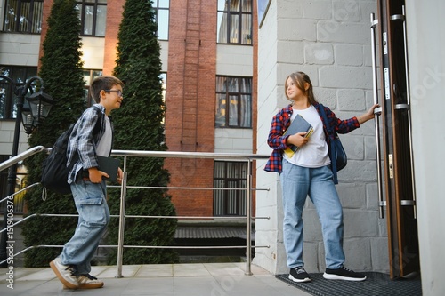 Wallpaper Mural Happy schoolchildren near the school. A boy and a girl are primary school students. School friendship Torontodigital.ca
