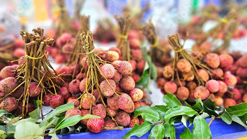 Lychee harvest showcase: a close-up shot captures bundles of ripe, succulent lychees on display, the vibrant fruit with their enticing red skin and tied together.