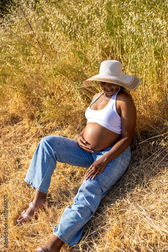A serene pregnant woman enjoys a tranquil moment outdoors, showcasing her baby bump and embracing love and connection during warm summer days, reflecting a joyful bond with her baby