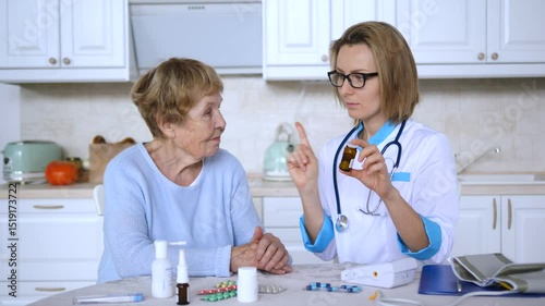 Senior woman attentively listening to medical professional providing detailed medication instructions within bright, comfortable kitchen setting during home healthcare consultation