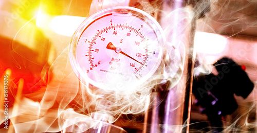 Pressure gauge displaying high readings in a manufacturing facility with smoke and steam present