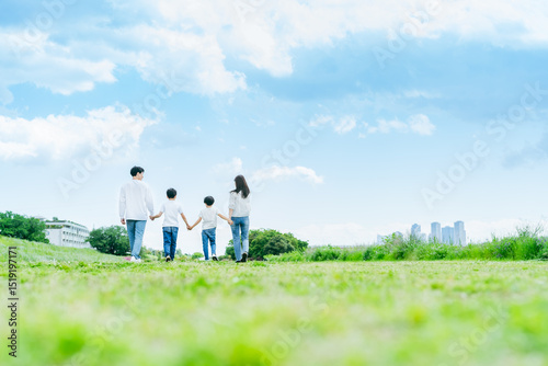 青空の草原を歩く家族