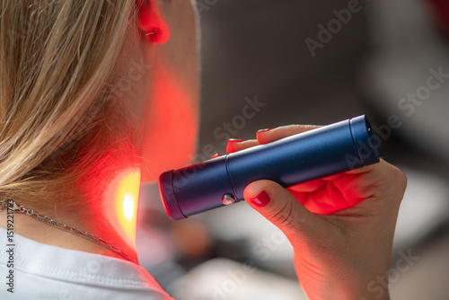Woman receiving red light therapy on her neck, known for reducing inflammation, easing pain, and stimulating collagen production to improve skin elasticity and overall neck health.