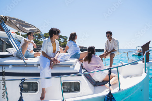 Group relaxing on traditional Mallorcan llaüt in turquoise water - Friends enjoying a sunny day on a Mallorcan boat Llaüt near rocky coast. Concept of summer, lifestyle, boat rental