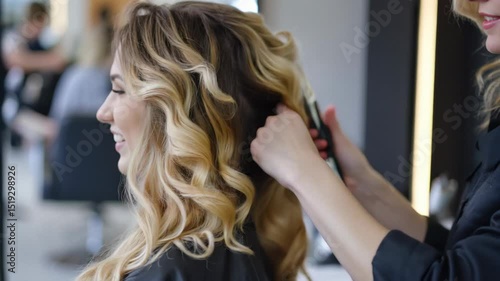 Smiling blonde woman getting her curly hair styled by a hairdresser in a modern salon