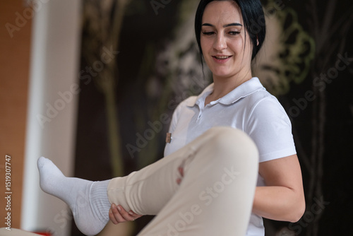 Physiotherapy Session with Blue Foam Roller.A therapist guiding a patient through leg exercises with the help of a blue foam roller in a therapy clinic. photo