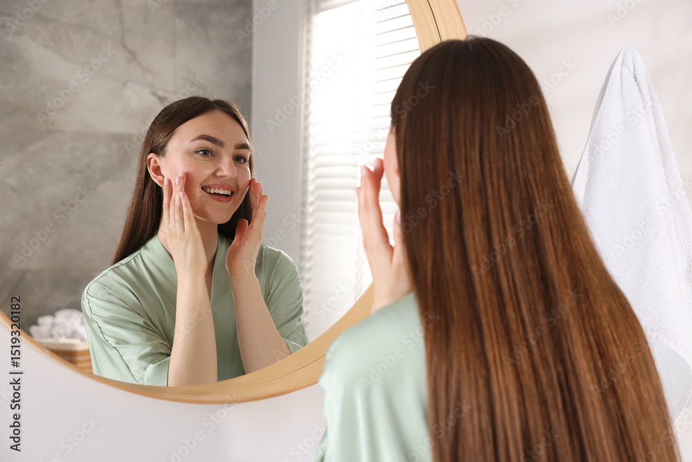Fototapeta premium Beautiful woman looking at herself in mirror indoors