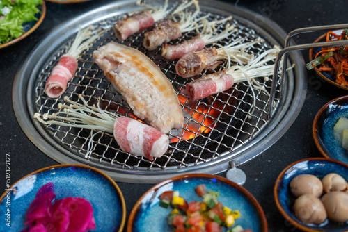 A grill that has meat and colorful vegetables cooking on it