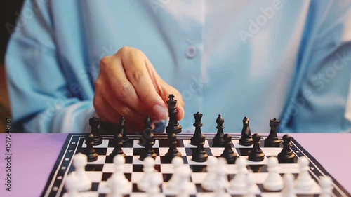 Person Wearing Blue Shirt Contemplating Chess Game with Black and White Pieces on Board in Modern Setting