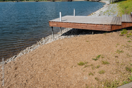 Fototapeta Naklejka Na Ścianę i Meble -  A beautifully crafted wooden dock nestled beside a tranquil lake beckons all visitors to come and relish the calm waters and the stunning, picturesque scenery that surrounds it