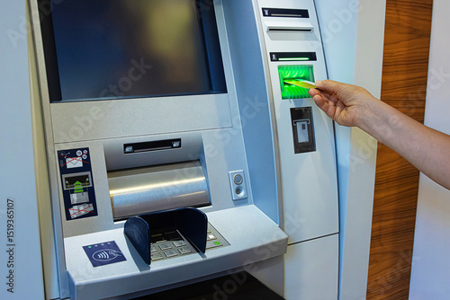 Photos A person inserts a bank card into an ATM slot, initiating a secure banking transaction