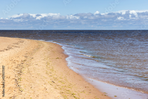 Fototapeta Naklejka Na Ścianę i Meble -  Calm sandy shoreline with soft waves lapping onto the coast