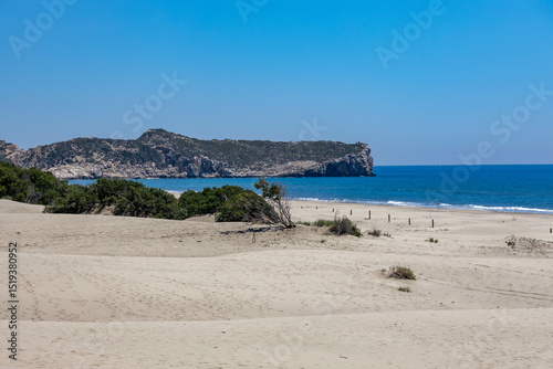 Fototapeta Naklejka Na Ścianę i Meble -  Panoramic view of Patara Beach with turquoise sea, sandy shore, green-covered cliff and clear blue sky. Antalya Province, Turkey, Mediterranean.