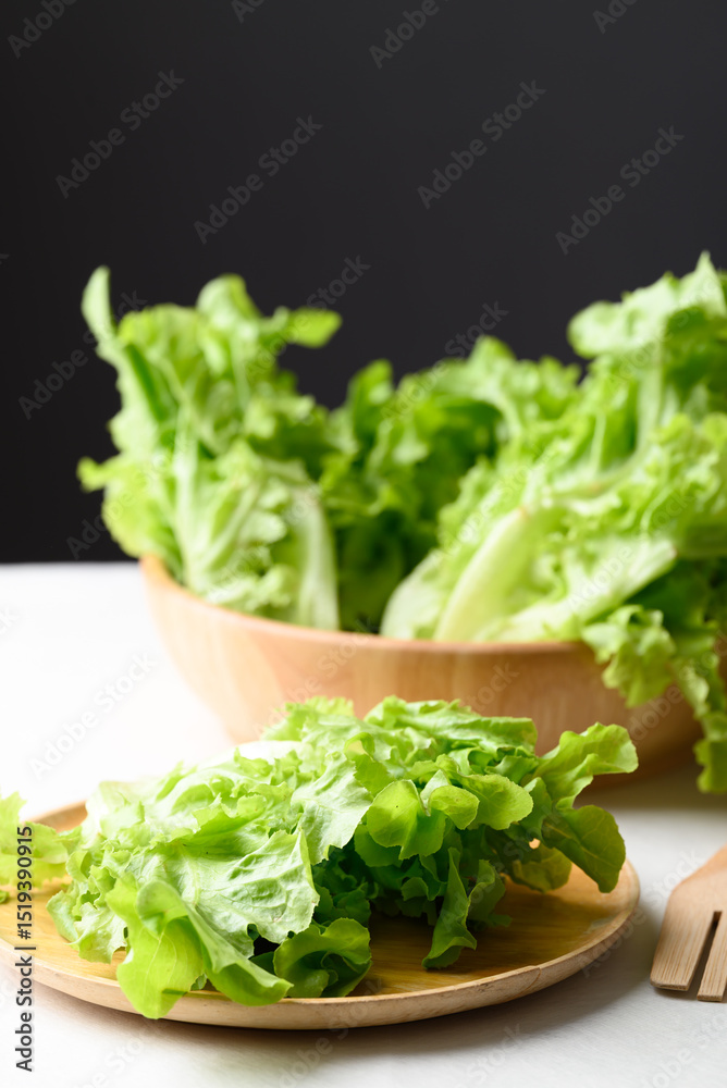 Organic green oak lettuce on wooden plate and bowl, Fresh vegetable, Healthy eating Organic green oak lettuce on wooden plate and bowl, Fresh vegetable, Healthy eating