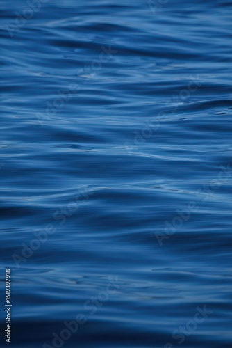 Close-up view of smooth blue ocean water surface with gentle ripples reflecting sunlight