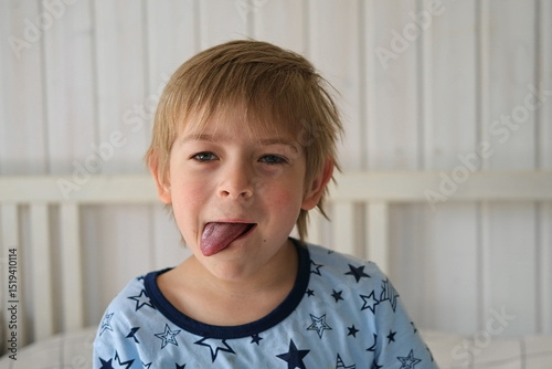 Boy joking, sticking tongue out with silly expression. Child making face. Funny foolishness portrait of little baby boy on white background. Adorable Caucasian kid making crazy and comical gesture. photo