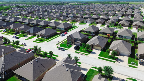 Row of new construction homes and large residential street with young trees immature landscaping at master planned community near Beauchamp Boulevard in Princeton, Texas, two story houses, aerial