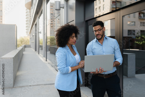 Foto Two business multiracial partners using laptop outside office discussing investm