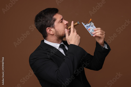 Greedy banker lighting cigar with dollar banknote on brown background