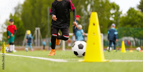 Young Soccer Player Dribbling Ball Through Yellow Training Cones During Youth Practice on Outdoor Field