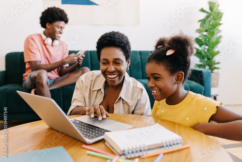 Mother and daughter engaged in home learning with a laptop