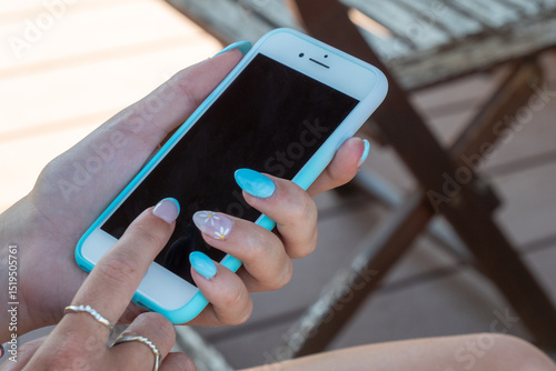 Woman is holding a blue cell phone with a manicured hand
