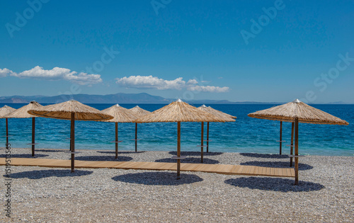 Fototapeta Naklejka Na Ścianę i Meble -  straw umbrella on a beach of white pebbles n Peloponnese, Greece with their well drawn shadow in front beautiful sea