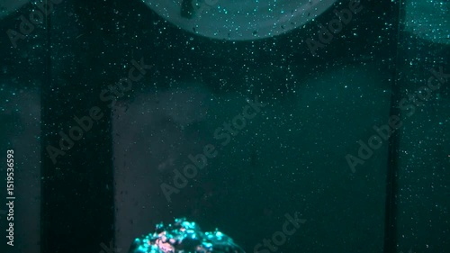 The texture of the water is a rumbling chaos with bubbles created by the air escaping outside in the blue light.