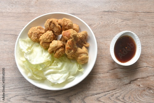 deep fried crispy fish ball dressing sweet chili tamarind sauce and slice cabbage on plate