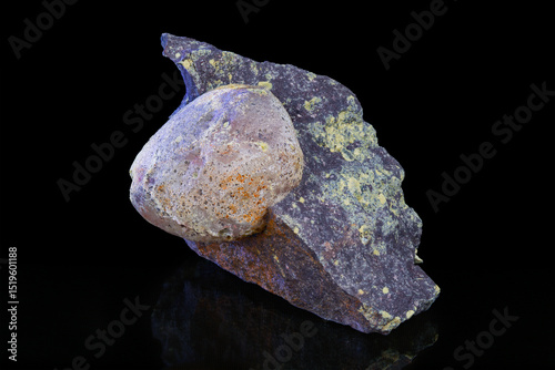 Natural uncut agate precious stone inside melaphyre vesicle on a black background. Closeup a nodule of gem in basalt volcanic igneous rock. Mineral piece with origin near Nova Paka, northeast Bohemia.