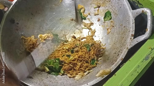 process of cooking oriental fried noodles on a frying pan